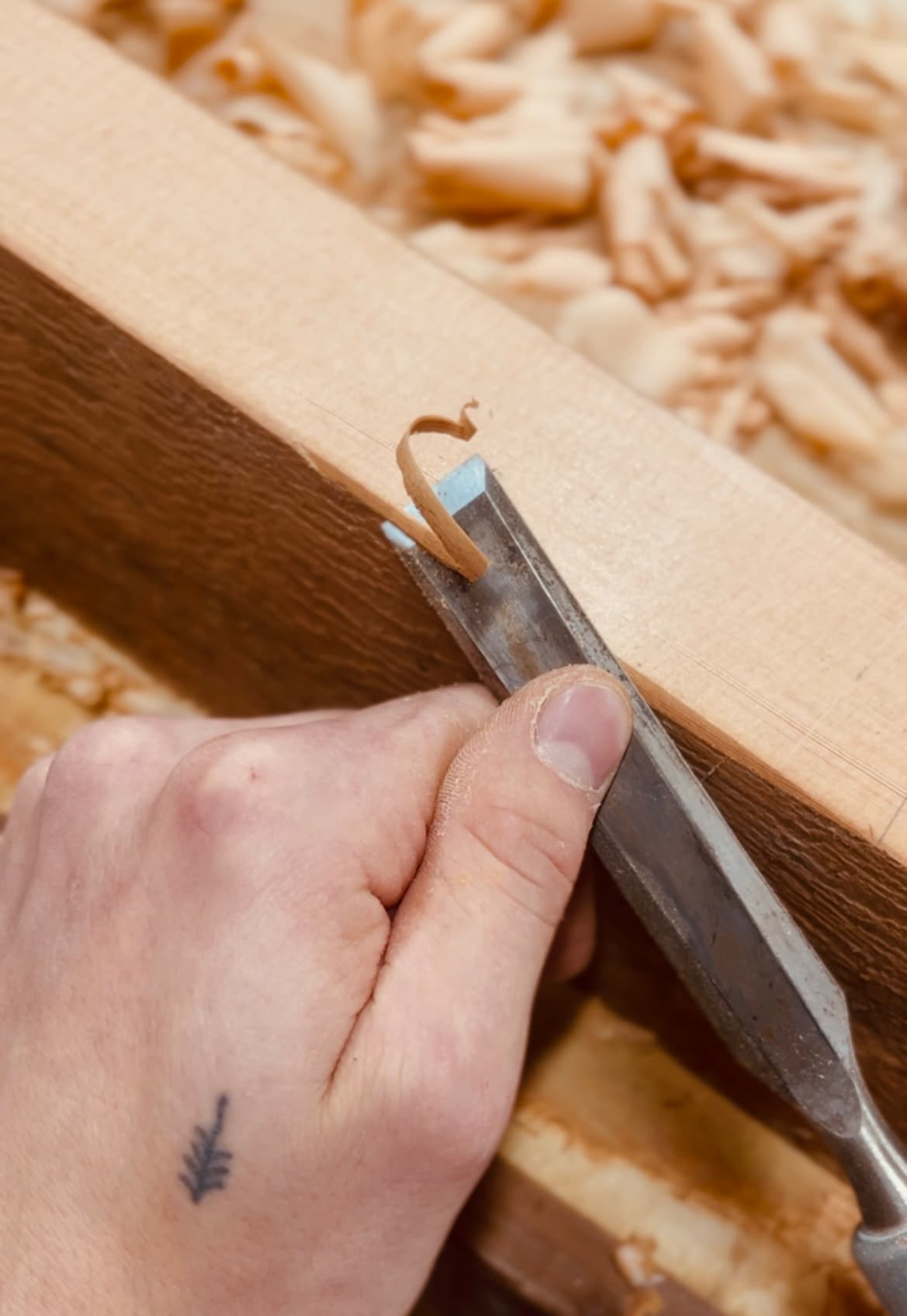 Master craftsman hand cutting joinery on a cedar beam